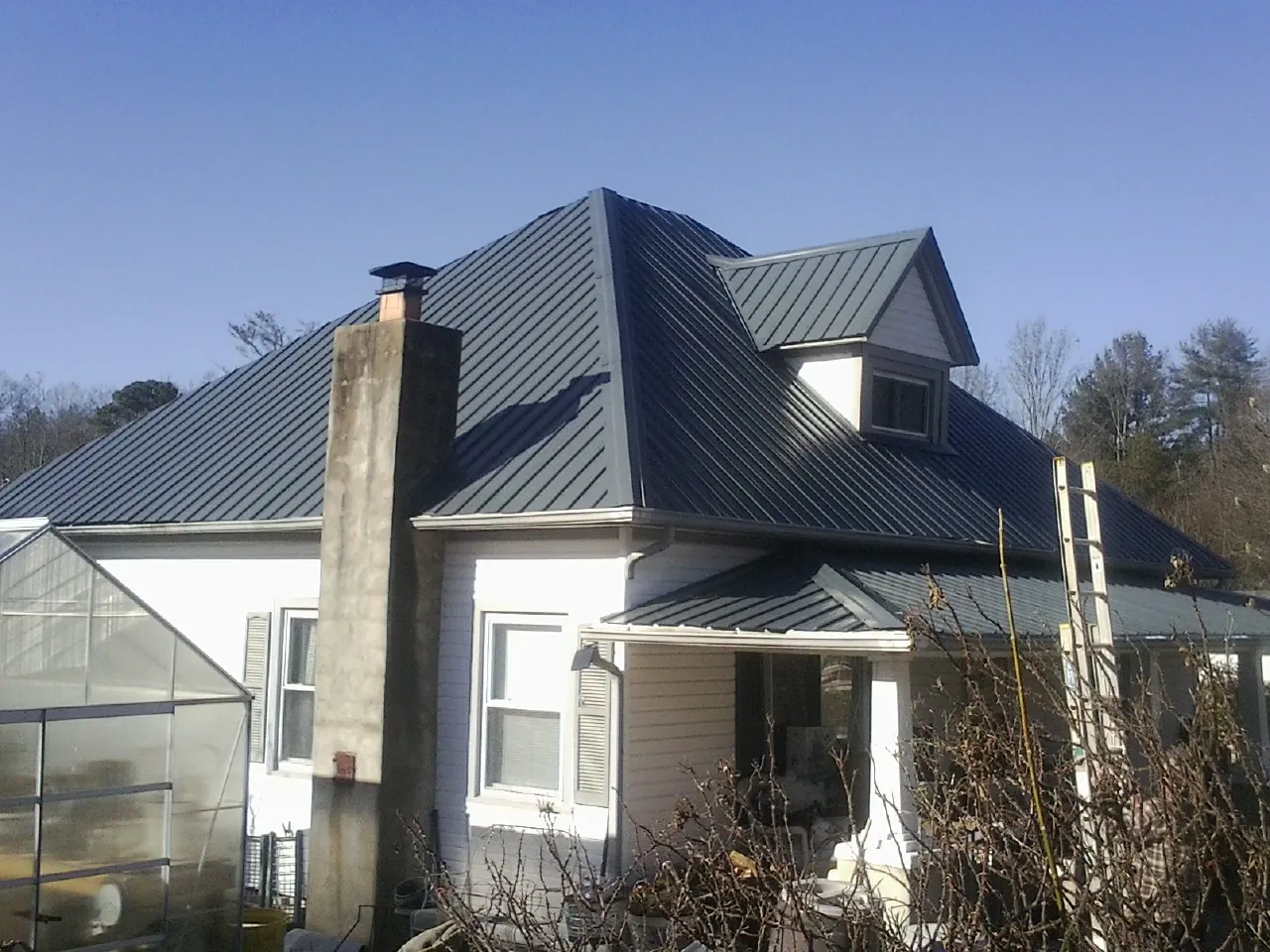 Dark blue standing seam metal roof on a white farmhouse with dormer — Slate & Tile Roof Repair by Roofing Brothers in Herndon