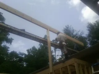 Carpenter setting a ridge beam over a new addition frame — Ice Dam Removal by Roofing Brothers in Herndon