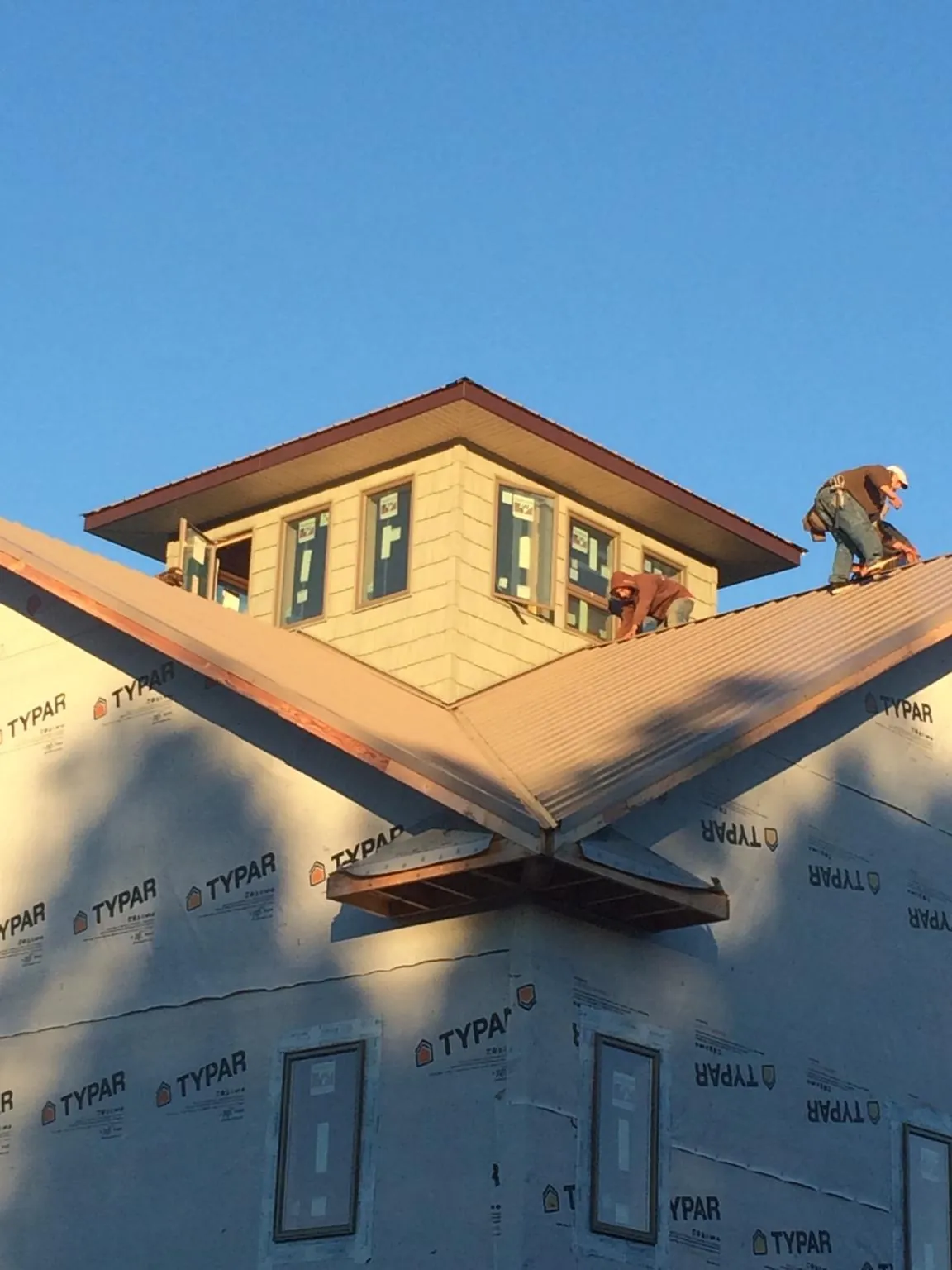 Roofers working around a rooftop cupola on a new metal roof at sunset — Roof Waterproofing in Herndon by Roofing Brothers